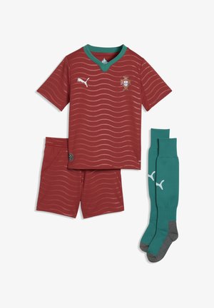 Czerwony strój piłkarski Portugalii z koszulką z krótkim rękawem, szortami i turkusowymi skarpetami; koszulka posiada faliste linie, logo Puma i herb Portugalii.