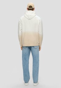 Sudadera con capucha en blanco con un degradado beige, material de algodón y un bolsillo tipo canguro; combinada con jeans de mezclilla azul claros.