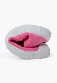 Baskets en toile rose avec une semelle en caoutchouc blanche, présentant un bout rond et un col rembourré. La chaussure est légèrement éraflée, montrant des signes d'usure.
