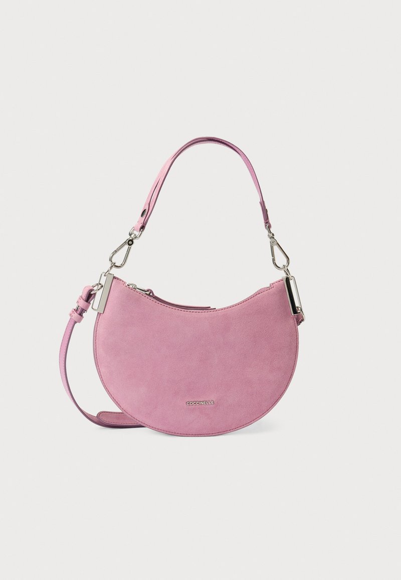 Roze suède handtas met een halvemaanvorm, voorzien van een afneembare riem en zilveren hardware accenten. Soepele textuur, minimalistisch ontwerp.