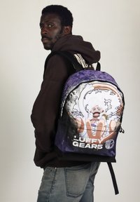 Mochila oscura con un gráfico colorido de un personaje con un peinado rizado blanco y una pose dramática, etiquetado prominentemente como "LUFFY GEARS5."