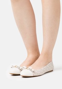 Balerinák fehér bőrből készült orral, bézs mintás szövet felsőrésszel, masni díszítéssel az orrán és alacsony profilú kialakítással.