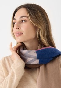 Multikleurige sjaal met geometrische patronen in tinten blauw, roze en beige, gemaakt van zacht, textuurmateriaal.