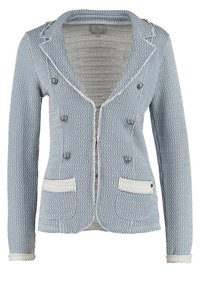 Ljust blå vävd jacka med ett strukturerat mönster, dubbelknäppt front, två framfickor och vit kant runt kragen och fickorna.