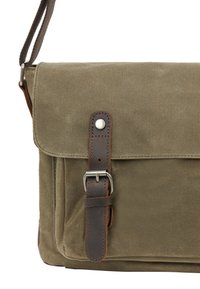 Olivenfarvet lærred messenger taske med en brun læderrem og sølvhardware; har et fold-over låg og frontbuckle detalje.