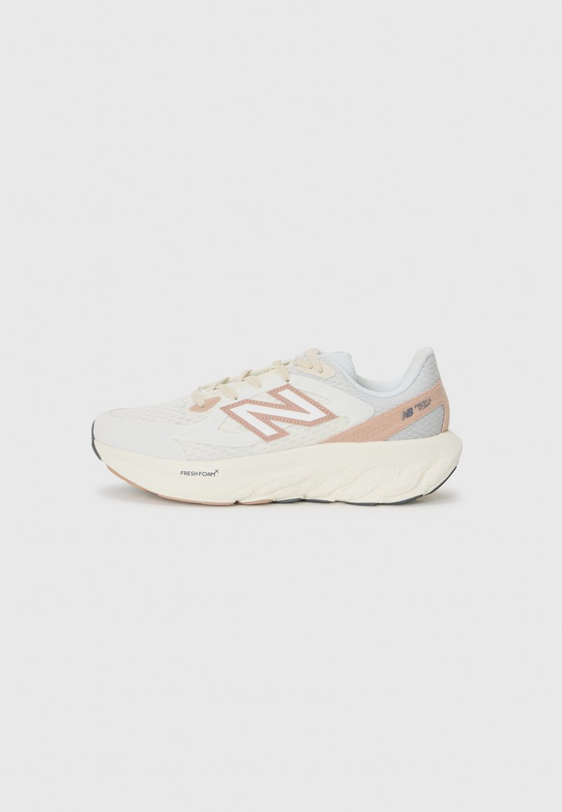 Baskets de sport blanches avec une tige en maille respirante, des accents roses clairs et une semelle rembourrée. Présente le logo New Balance sur le côté.