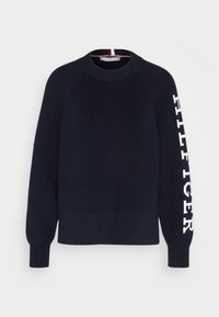 Marineblauer Strickpullover mit Rundhalsausschnitt, gerippten Bündchen und einem weißen Logo auf dem Ärmel. Hat ein strukturiertes Strickmuster und einen kontrastierenden Innenkragen.