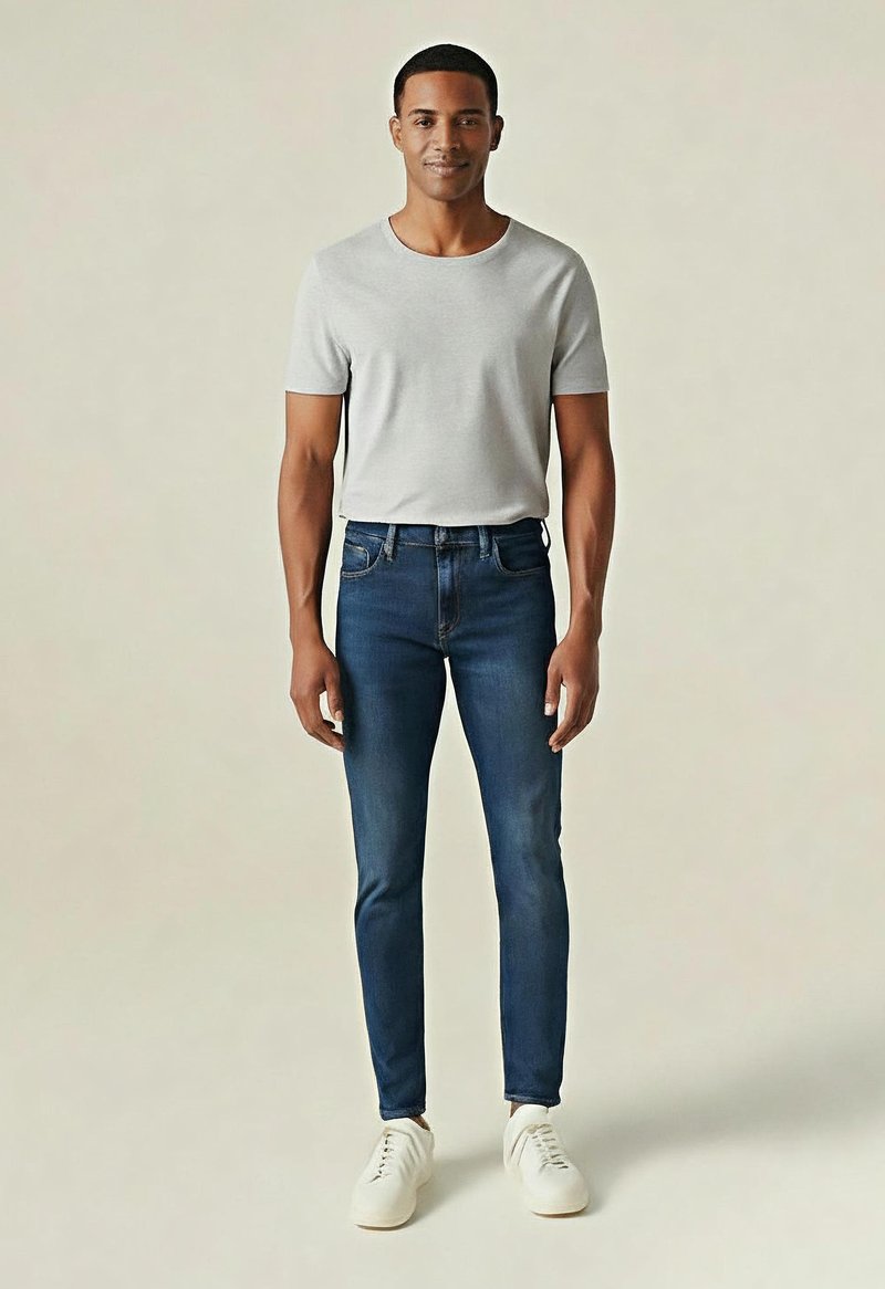 Jasnoszara koszulka z krótkim rękawem w połączeniu z ciemnoniebieskimi jeansami slim fit i białymi trampkami; prosty design i gładka faktura.