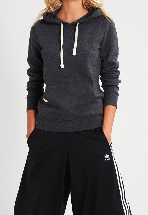 Hoodie gris foncé avec une poche kangourou, des cordons crème, des poignets et un ourlet côtelés, associé à un pantalon noir à jambes larges avec des rayures.