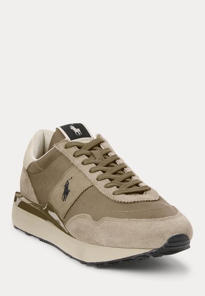 Beige mocka- och tygsneaker med bruna snören, vadderad sula och svart broderad logotyp på sidan och tungan.
