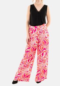 Top negro sin mangas con borde de encaje, combinado con pantalones anchos de cintura alta en un patrón floral rosa y blanco, finalizando con tacones negros.