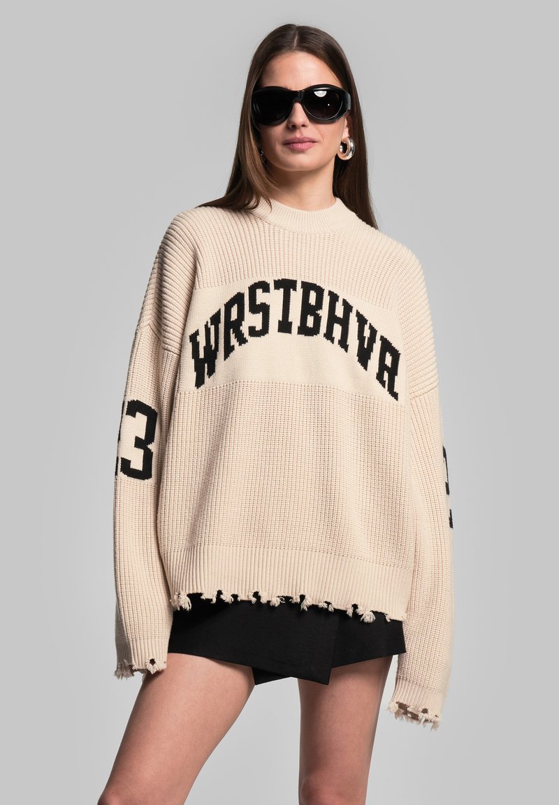Beige gestrickter Pullover mit lockerem Schnitt, ausgestattet mit schwarzem Text "WRSTBHVR" und der Nummer "3" an den Ärmeln sowie rohem Saumdesign.