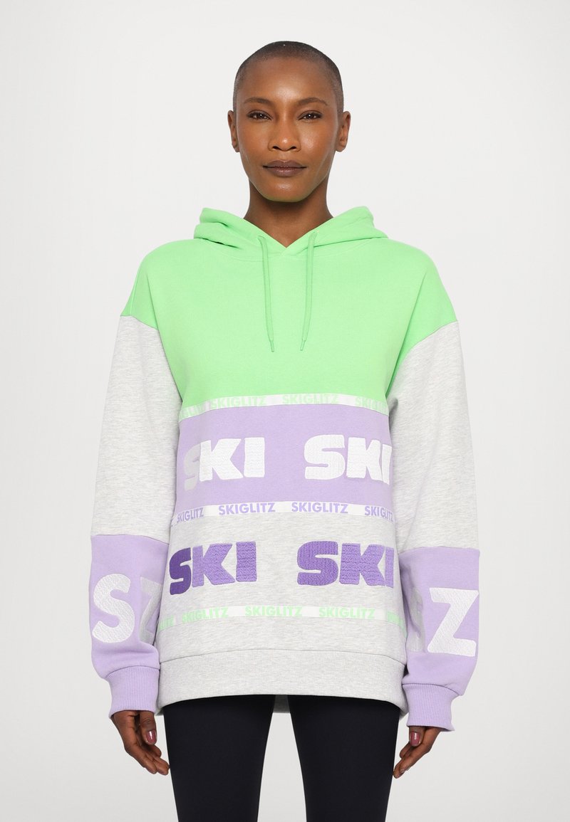 Hooded sweatshirt in green, grey, and lavender with large "SKI" lettering. Features a relaxed fit and textured fabric accents.