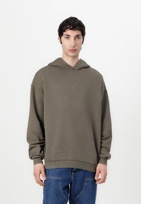 Oversized olive green hoodie with a front pocket, ribbed cuffs, and hem. Subtle branding displayed in light gray on the chest.