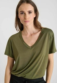 Olijf groene V-hals T-shirt van een gladde, lichte stof met korte mouwen en een relaxte pasvorm, met subtiele textuur.