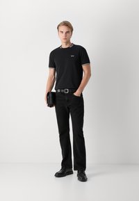 Sort kortærmet t-shirt med krave i hvide striber, med et lille logo på brystet. Matchet med sorte lige jeans og sorte sko.