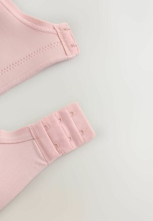 Pink bra clasp with three hook and eye closures on a light gray background, showing stitching and fabric texture.