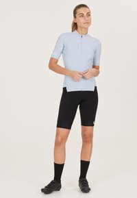 Lichtblauw fietsjersey met een korte rits, gecombineerd met zwarte fietsshorts. Heeft een slanke pasvorm en contrasterende accenten op de mouwen.
