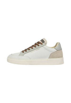 Sneaker bassa bianca con tacco in suede beige, dettagli grigi, lacci marroni e suola in gomma color crema. Nome del marchio sul lato e sulla linguetta.