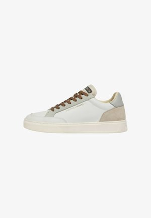 Sneaker bassa bianca con tacco in suede beige, dettagli grigi, lacci marroni e suola in gomma color crema. Nome del marchio sul lato e sulla linguetta.
