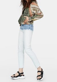 Multicolored geblokte bomberjack, lichtblauwe skinny jeans en zwarte platform sandaal met verstelbare banden.