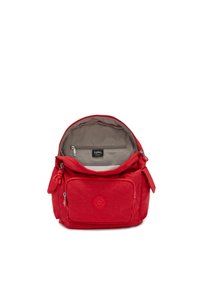 Mochila de tela roja con cierre superior de cremallera, forro gris, bolsillo frontal y un logo redondo. Incluye un encanto en la tira de la cremallera.