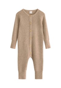 Ribbad beige jumpsuit med långa ärmar, knäppning fram och muddar vid anklarna. Tillverkad av ett mjukt material med en texturerad yta.