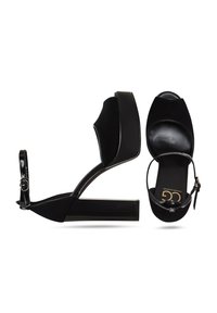 Schwarze High-Heel-Sandalen mit glänzender Oberfläche, breiter Plateausohle, offenem Zehendesign und verstellbarem Knöchelriemen. Glattes Ledergefühl.