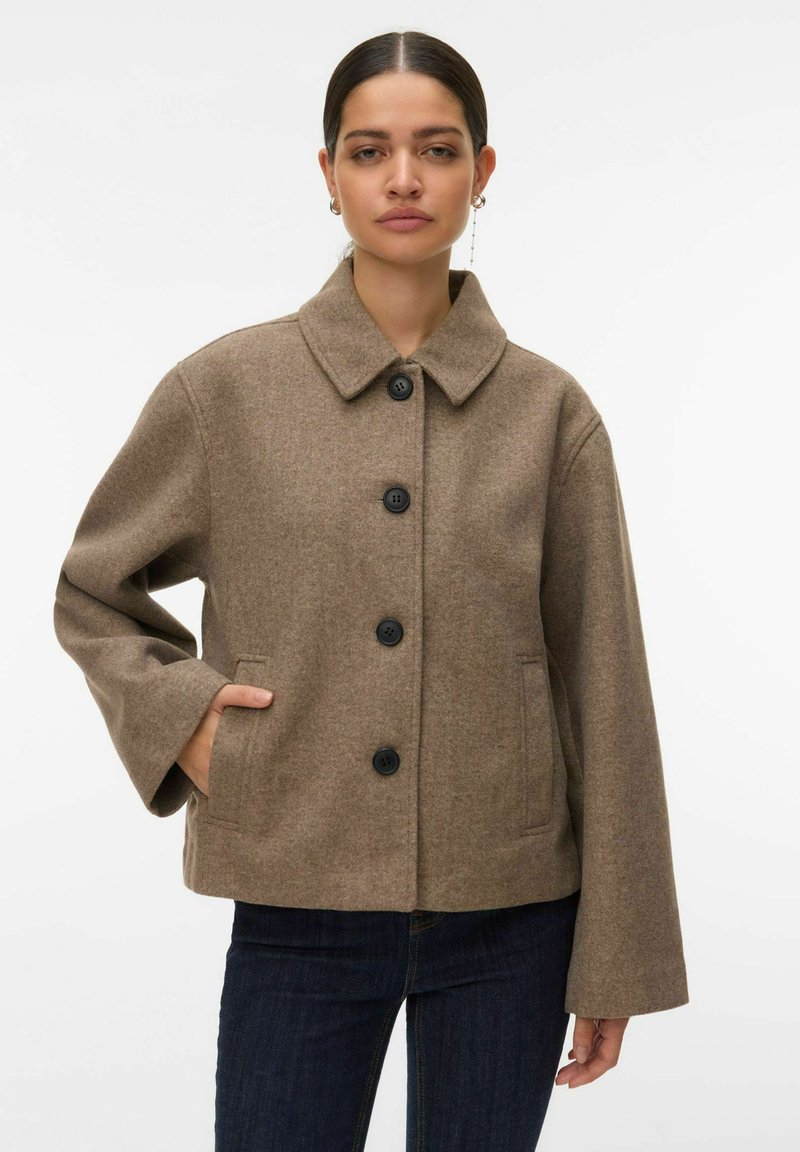 Barna gyapjúkeverék zakó széles gallérral, öt fekete gombbal, oldalzsebekkel és bő ujjakkal. Sima textúra, minimalista dizájn.