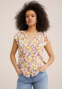 Blusa floreale con scollatura a V, maniche corte e fondo bianco decorato con motivi floreali rosa e gialli. Tessuto confortevole con vestibilità rilassata.