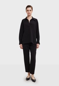 Zwarte overhemd met lange mouwen en een kraaghalslijn, gecombineerd met zwarte rechte broek en lage zwarte ballerina's. Smooth textuur van de stof.