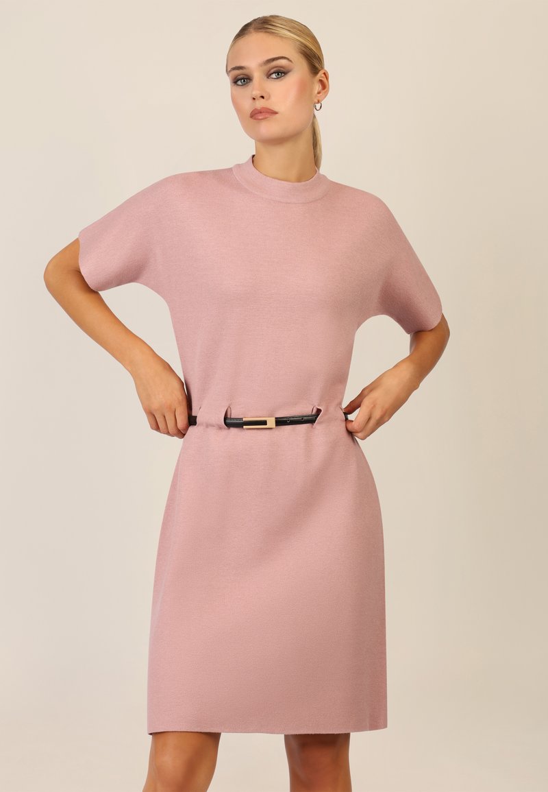 Vestido de punto rosa hasta la rodilla con un cuello alto, mangas cortas y un cinturón negro con un acento dorado en la cintura.