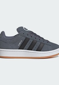 Zapatillas deportivas de ante gris con rayas negras, media suela blanca y suela de goma. Presentan una puntera redonda y cierre de cordones.