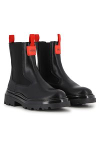 Botas Chelsea pretas em couro com painéis laterais elásticos, tiras vermelhas contrastantes, solas grossas de borracha e detalhes sutis de costura.