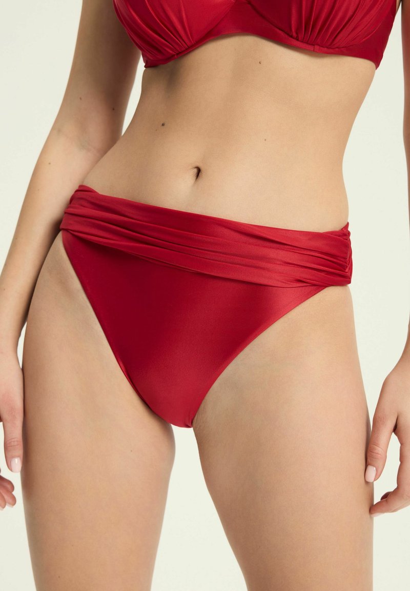 Czerwony dół bikini z miękkiego, elastycznego materiału. Posiada plisowaną talię i wysokie nogawki, oferując smukłą i dopasowaną sylwetkę.