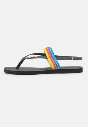 Sort gummiflipsandal med en flerfarvet stribet stofrem og justerbar ankelspænde, med en tekstureret fodseng.