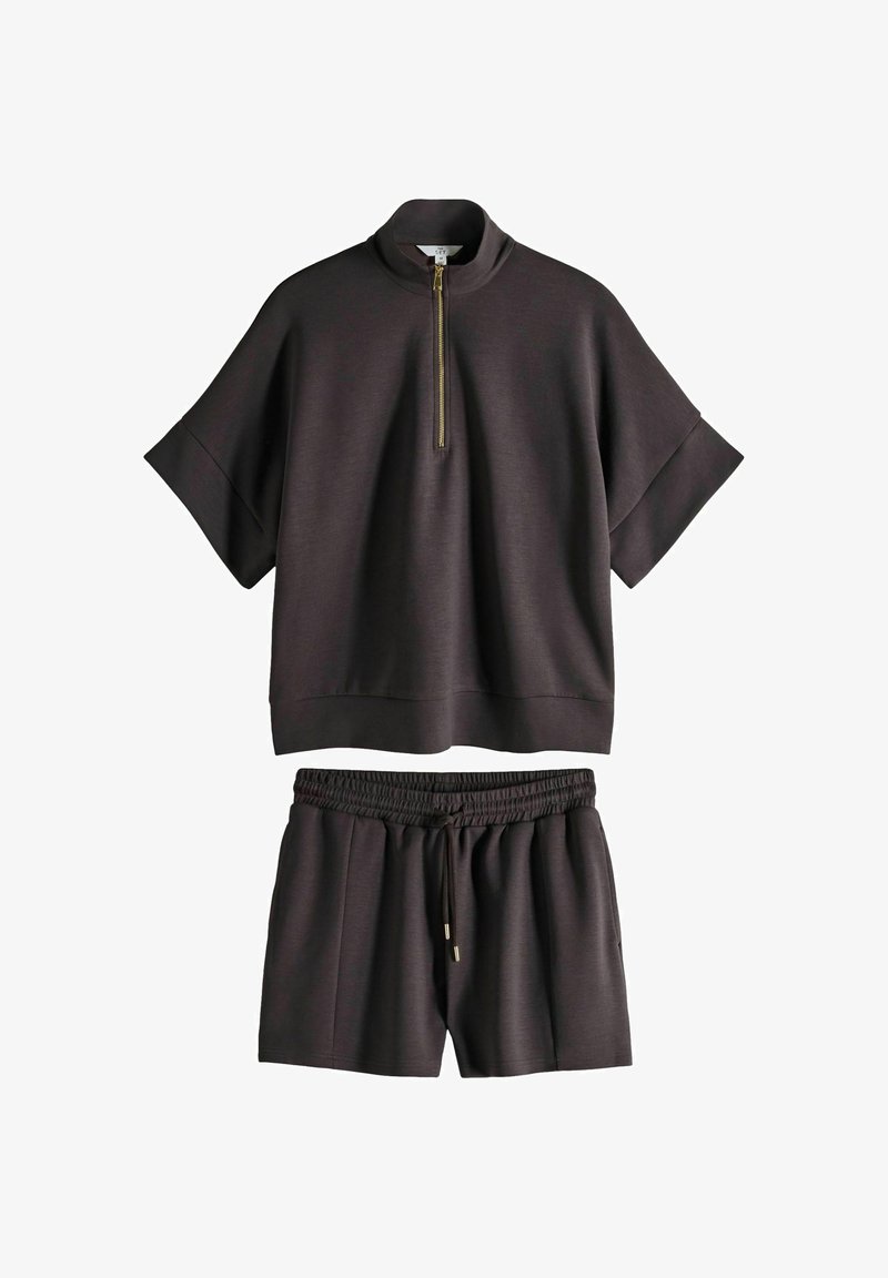 Mörkbrun avslappnad klädsel som inkluderar en kortärmad topp med kvartdragkedja och matchande shorts med elastisk midja och snörning.