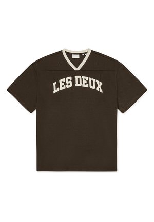 Pruun lühikeste varrukatega särk ümarate V-kaelusega, millel on valged sõnad "LES DEUX" rinna peal ja võrkpaela tekstuur.