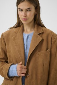 Brown suede blazer with a notch collar, single front pocket, and two front buttons; layered over a light blue fuzzy sweater.