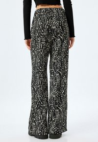 Zwart-wit gestreepte wijde broek met een gestructureerd oppervlak, hoge taille en subtiele flare aan de onderkant.