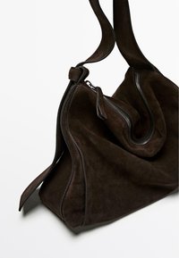 Brown suede handbag with a soft, slouchy shape. Features exposed zippers and contrasting trim detailing. Adjustable shoulder strap included.