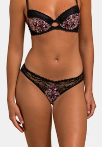 Ensemble de soutien-gorge et thong en dentelle noire avec un imprimé floral dans des teintes de rose, violet et crème. Le soutien-gorge présente un détail en trou de serrure et des bords festonnés.