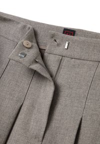 Pantalones gris ajustados con una textura suave, que presentan un cierre frontal con botón, cremallera y pliegues sutiles. Etiqueta de la marca visible en el interior.