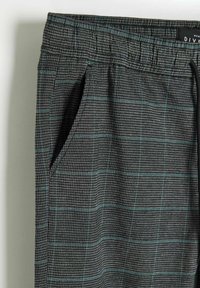 Szare i czarne małe spodnie w kratę z zielonym wzorem okienkowym, elastycznym pasem oraz boczną kieszenią.