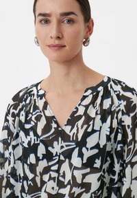 Zwart-wit gestreepte blouse met een zachte, doorschijnende textuur, v-hals en geplooide schouders, met blauwe accenten in het ontwerp.