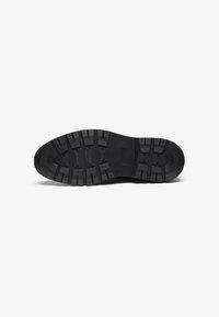 Schwarze Gummi-Schuhsohle mit einem strukturierten Griffmuster und markanten Profilrillen, mit einer abgerundeten Zehe und flachem Absatz.