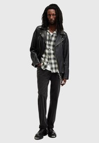 Veste en cuir noir de moto, chemise à carreaux, jean sombre et chaussures noires. Comprend des fermetures éclair, des boutons et un look superposé décontracté.