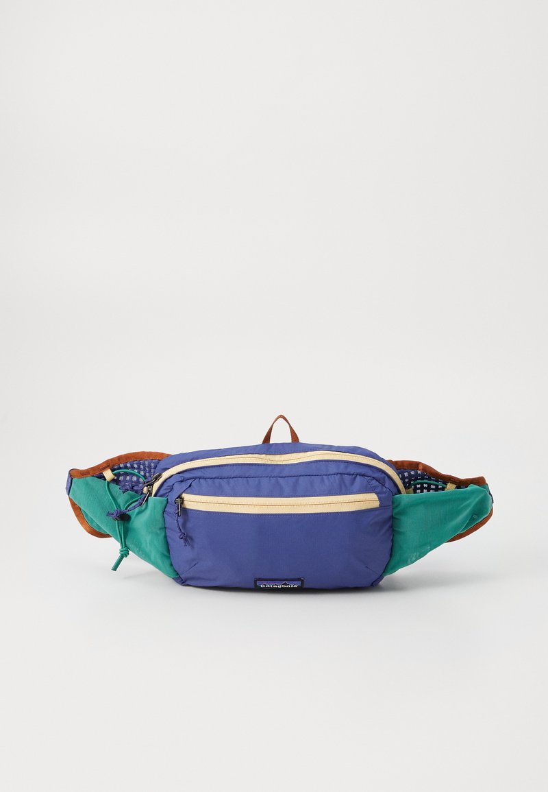 Fanny pakas su purpurine korpusu, žaliais akcentais ir dviem geltonais užtrauktukais. Yra ruda kilpa ir tekstūruota vidaus dalis. Lengvas audinio konstrukcija.