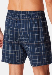 Boxer da uomo a quadri blu navy, realizzati in morbido cotone, con un motivo a griglia bianca e marrone, vita elasticizzata e orlo dritto.