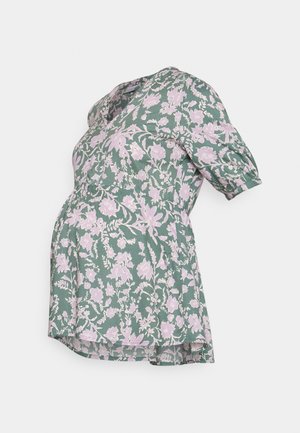 Blusa de maternidade em tecido verde com um padrão floral em rosa. Tem mangas curtas volumosas e um corte solto, ideal para uma barriga em crescimento.